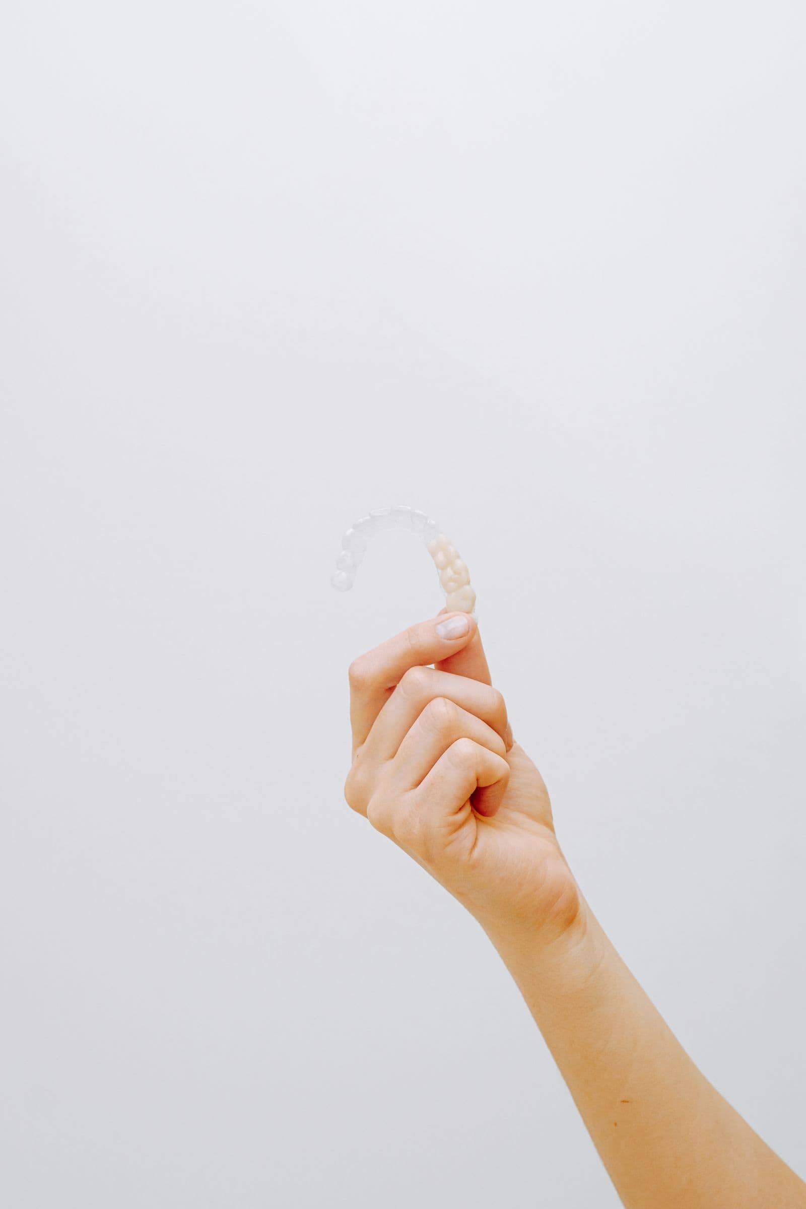 A hand holding a clear plastic aligner tray