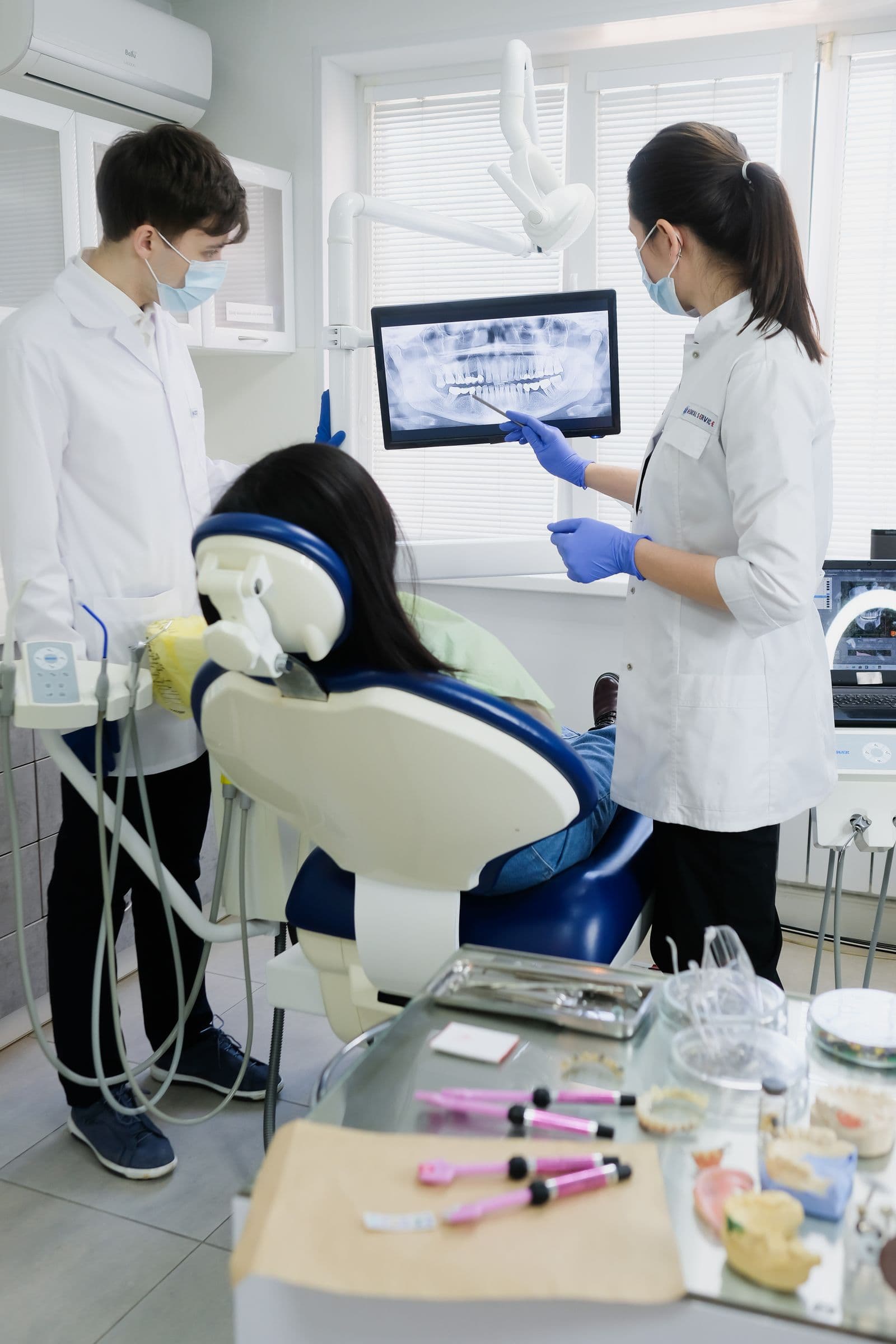 Two dentists reviewing a panoramic dental x-ray with a patient in the chair