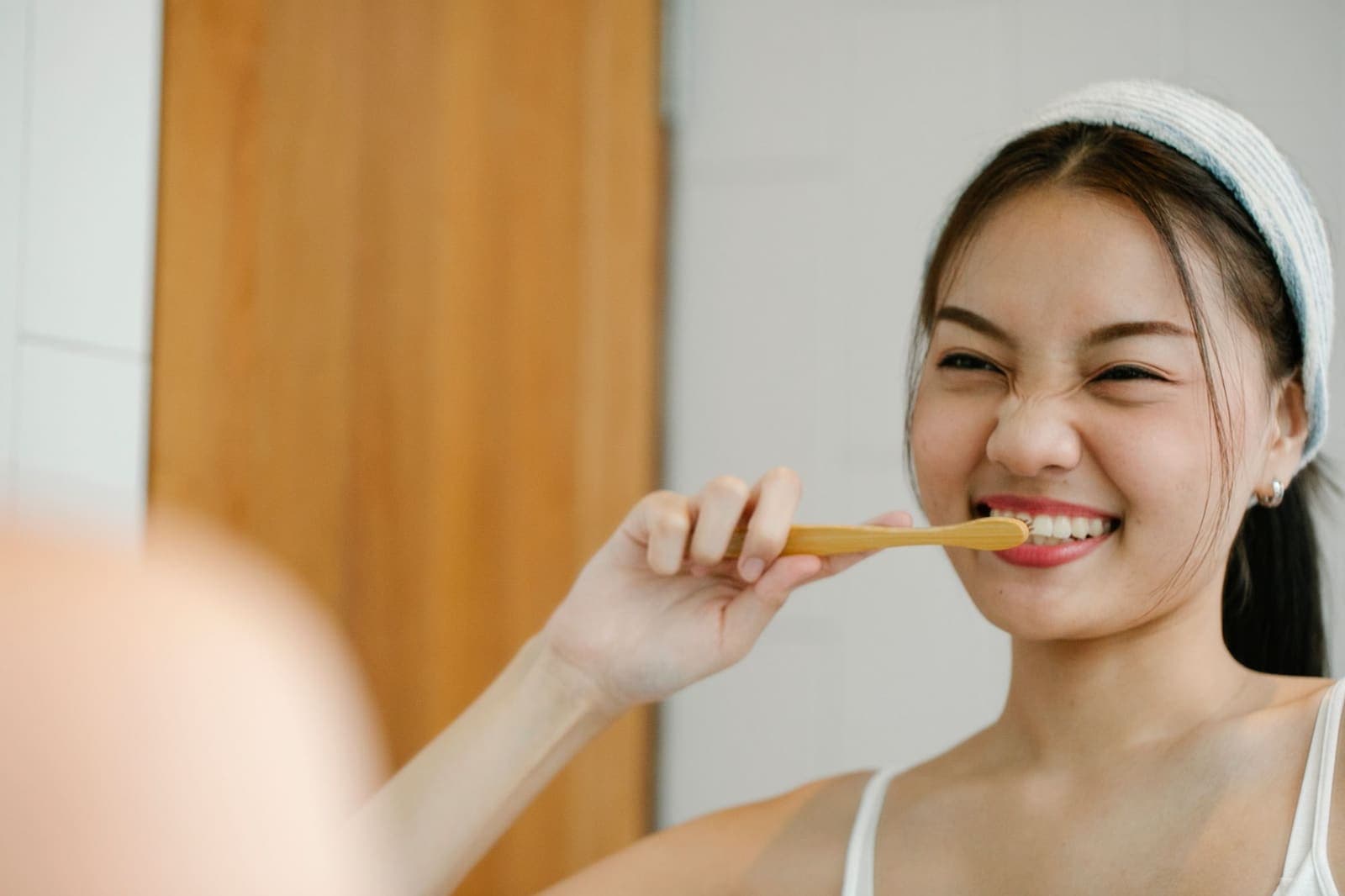 A woman smiling while brushing her teeth at home