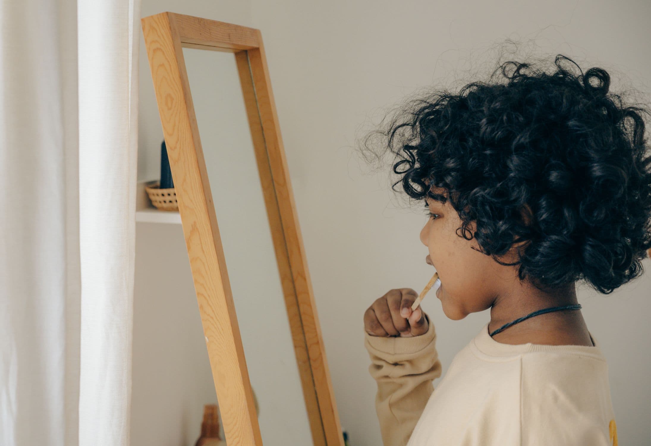 A young child brushing their teeth with a small toothbrush